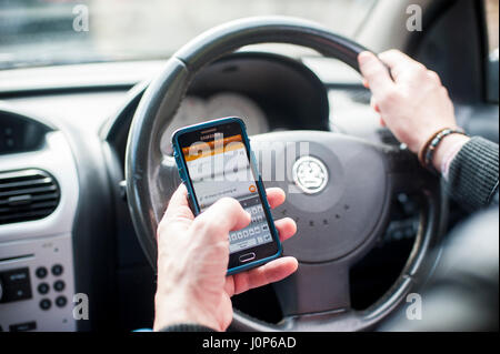man using mobile phone texting whilst driving Stock Photo