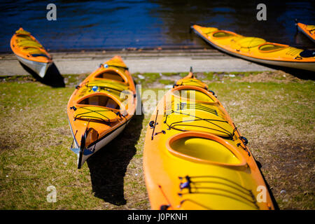 A group of yellow kayaks wait for clients on the footpath of the Yarra river, opposite the CBD, Melbourne, Australia Stock Photo