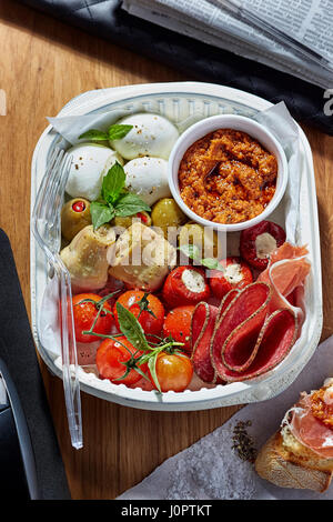 Antipasti lunch office - mozarella, artichoke, salami, red pesto, cherry tomatoes and feta stuffed peppers Stock Photo