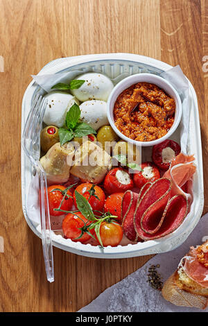 Antipasti lunch office - mozarella, artichoke, salami, red pesto, cherry tomatoes and feta stuffed peppers Stock Photo