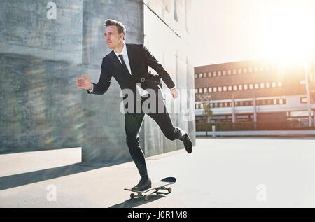 Handsome businessman taking a ride on a skateboard in the street. Stock Photo