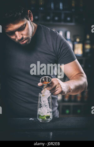 Young expert barman prepares a cocktail in a nightclub Stock Photo