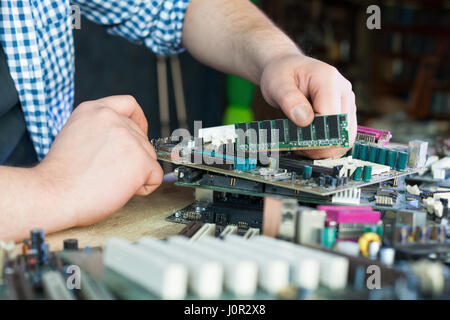 Service engineer work with broken computer motherboard. Electronic components repairing technology Stock Photo