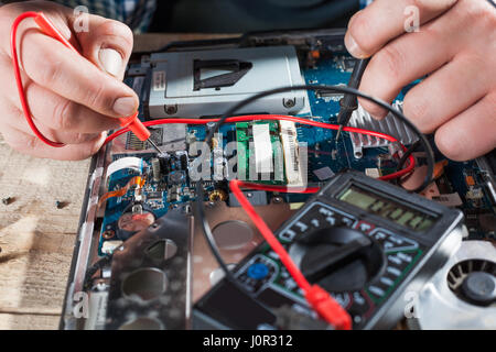 Male engineer hands diagnostics laptop with multimeter closeup view. Electronic devices repairing technology Stock Photo