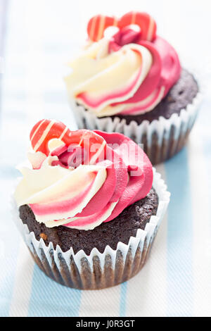 Chocolate cupcake with raspberry-vanilla frosting and heart shaped decoration Stock Photo