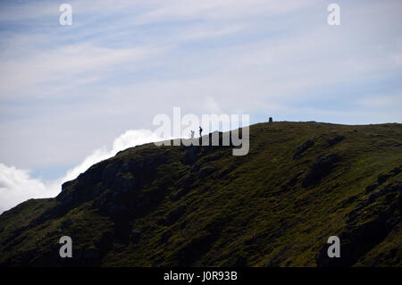 Silhouettes of a Pair of Walkers on the Summit of the Scottish Mountain Corbett Ben Ledi in the Trossachs National Park, Scottish Highlands. Stock Photo