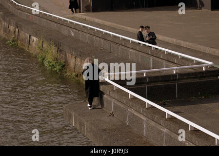 Young Chinese teenage tourists photographs tale selfie type pictures on the Clyde river Glasgow playing suicide Stock Photo