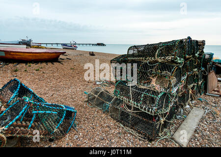 England, Deal beach. Lobster pots stacked on beach with Deal Pier in the back ground. Dawn, twilight period. Grey layers of cloud in sky. Stock Photo