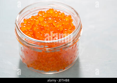 Trout caviar in jar on blue background Stock Photo