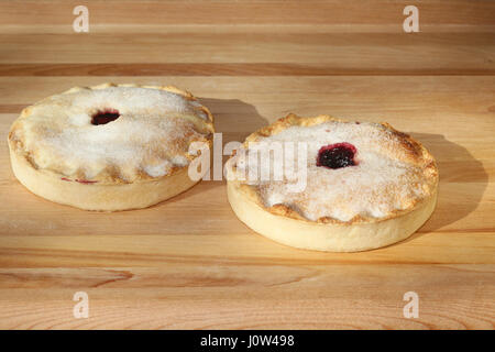 Cherry pie and and blueberry pie sprinkled with sugar on pastry board Stock Photo