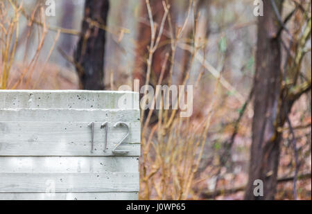 the number 112 on a concrete block in the woods, in Hampton bays NY Stock Photo