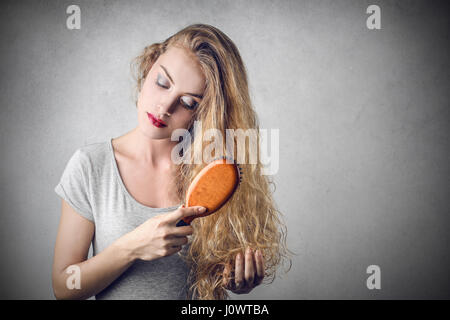 Young blond woman brushing her head Stock Photo