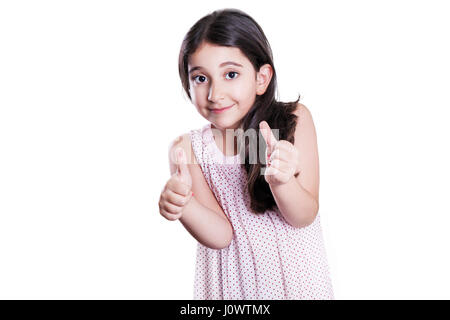 Beautiful happy little girl with long dark hair and dress looking at camera with thumbs up. studio shot, isolated on white background. Stock Photo