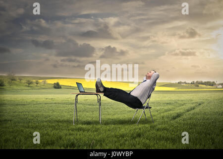 Businessman relaying on field Stock Photo