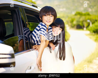 happy asian little boy and girl sticking their heads out of car window Stock Photo