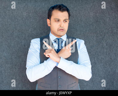 Closeup portrait of young business man thinking, daydreaming,pointing opposite directions, looking confused, isolated gray background. Negative emotio Stock Photo