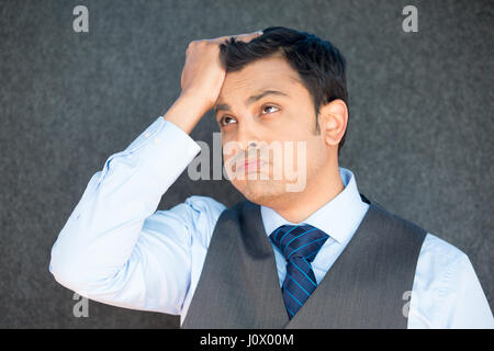 Closeup portrait, stressed young business man with vest and tie, hand on head uh oh, with bad headache, isolated gray black. Negative human emotion fa Stock Photo