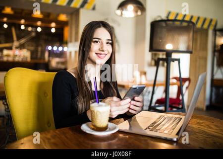Traveler sending emails with laptop and smartphone during coffee break Stock Photo