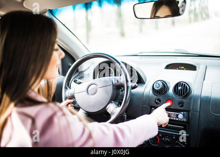 Female hand pressing emergency light button on car dashboard. Stock Photo