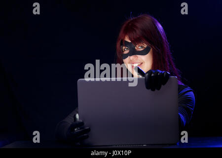 Thief in mask holds laptop Stock Photo