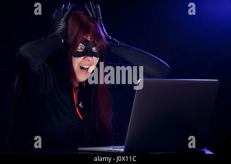 Surprised thief next to laptop Stock Photo