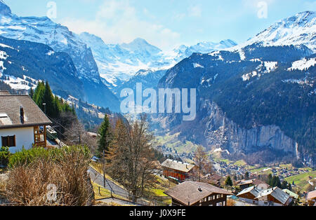 The sunny Lauterbrunnen valley with a gorgeous waterfalls and Alpine wooden houses, hidden among the snowy Alps, Wengen, Switzerland Stock Photo