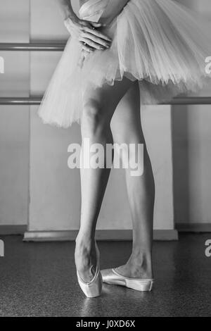 Ballerina in pointes and a pack warms up before the dance lesson. Long slender female feet. Classical ballet. Prima ballerina. Stock Photo