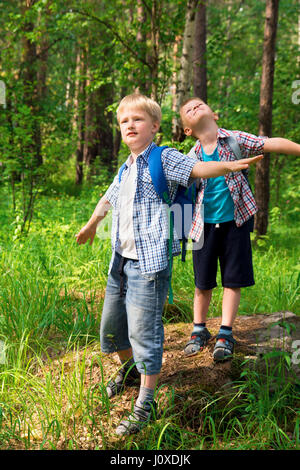 Children with backpacks walking in a summer forest, go hiking and having fun outdoor Stock Photo