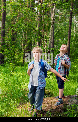 Children with backpacks walking in a summer forest, go hiking and having fun outdoor Stock Photo