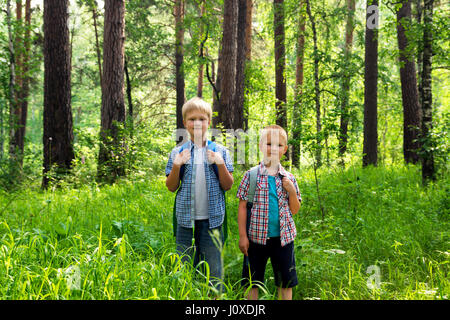 Children with backpacks walking in a summer forest, go hiking and having fun outdoor Stock Photo