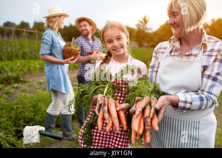 Girl with grandmother showing carrots from own garden Stock Photo