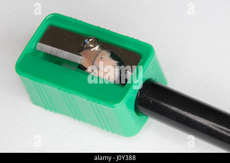 Green pencil sharpener with a black pencil on a white background Stock Photo