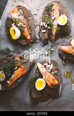 Sandwiches with sardines and quail eggs on the table vertical Stock Photo