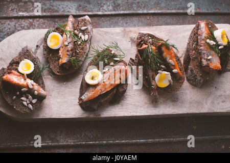 Sardines, quail egg on rye bread on the stand horizontal Stock Photo