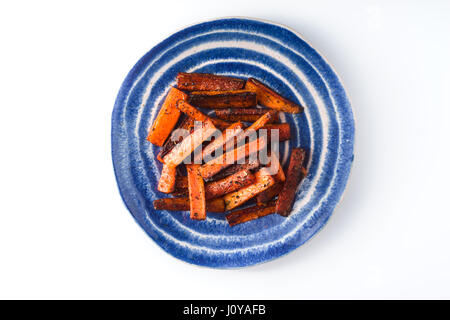 Roasted carrots on a blue plate on a white background horizontal Stock Photo