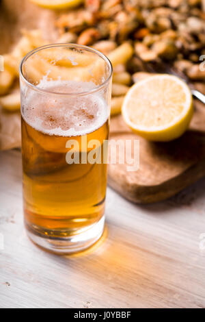 Glass of beer with blurred snack on the white wooden table Stock Photo