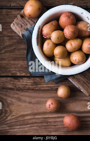 Raw potatoes in the metal bowl on the wooden table top view Stock Photo