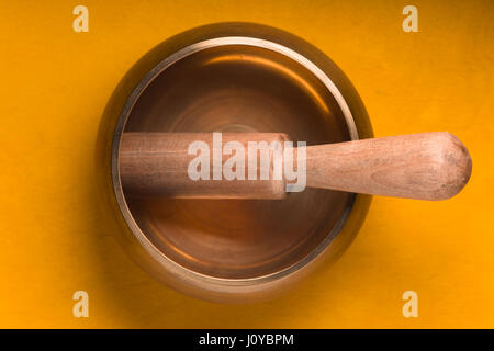 Metal bowl with a wooden stick on a yellow table Stock Photo