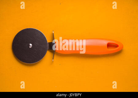 Pizza knife on the yellow table top view Stock Photo