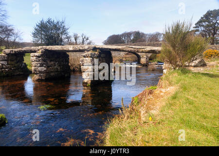 Ancient clapper bridge over the East Dart river at Postbridge, Dartmoor, UK.  The road bridge is behind. Stock Photo