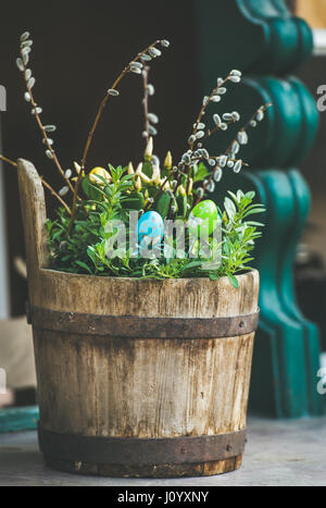 Green plants, colored eggs, willow tree branches in wooden tub Stock Photo