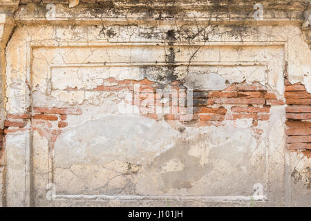 Broken, old and dirty plastered wall revealing old brick wall. Stock Photo