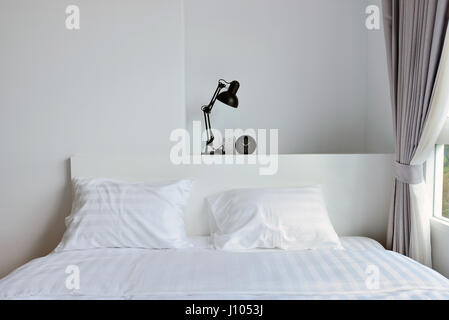 modern lamp on wooden nightstand in white modern bedroom, interior design Stock Photo