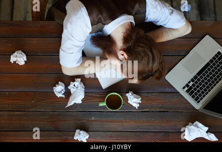 Tired man with his head on workplace napping after work Stock Photo