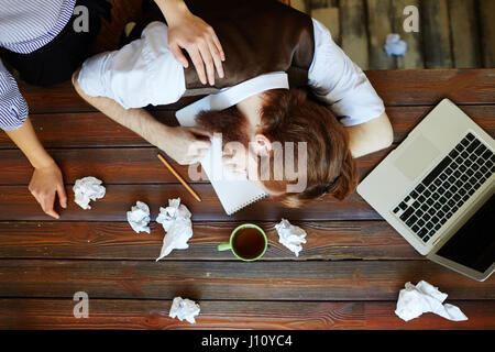 Woman waking up her co-worker sleeping on workplace Stock Photo