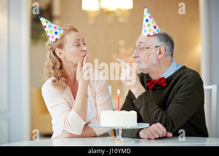 Senior couple having birthday fun by table Stock Photo