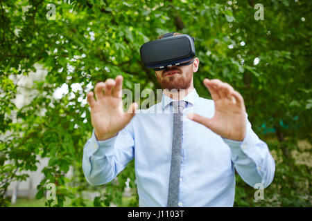 Portrait of man wearing VR gear experiencing nature walking in forest in real world Stock Photo
