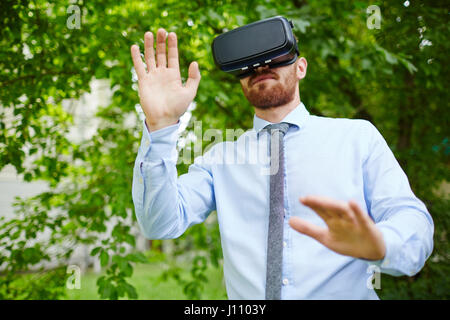 Relaxing VR: Portrait of man wearing VR glasses experiencing forest and sounds of nature Stock Photo