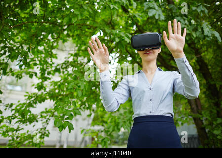 Portrait of female office worker wearing VR glasses experiencing forest and sounds of nature to relieve stress Stock Photo