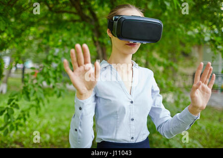 Portrait of young woman wearing VR headset instead of enjoying real nature Stock Photo